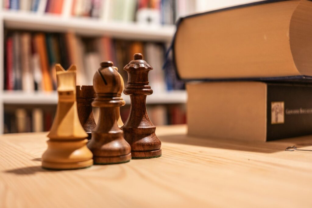 A wooden chess set sitting on top of a table next to a book